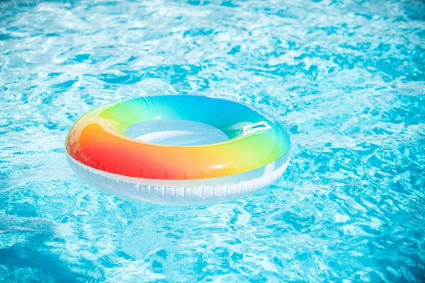 Anillo inflable en piscina azul. Juguete inflable colorido en el agua de la piscina, fondo de vacaciones de verano. — Foto de Stock