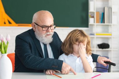 Üzgün okul çocuğu torunu kitap okuma ve yazma konusunda yaşlı büyük öğretmenle sorun yaşıyor. Sıkı çalışma konsepti.
