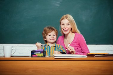 Gülümseyen genç öğretmen ve küçük öğrenci bir sınıfta..