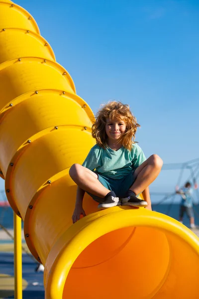미끄럼틀 놀이터에 있는 애. 아이들 공원에서 재밌게 놀고 있는 귀여운 소년. — 스톡 사진