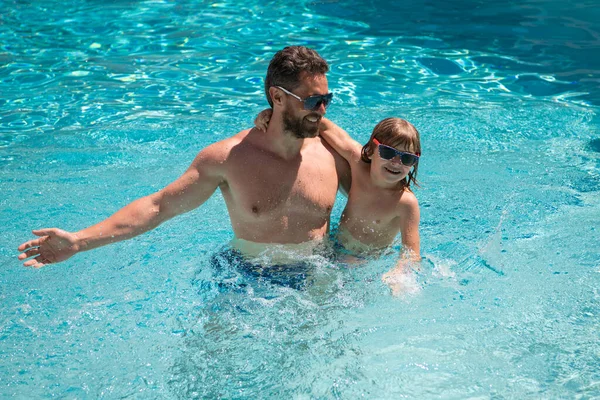 Vader en zoon zwemmen in het zwembad, zomerfamilie. Kind met papa die in het zwembad speelt. Zomervakantie. Aquapark. Vader en zoon vrije tijd. — Stockfoto