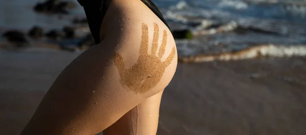 Sandy sexy womans buttocks with sand hand prints. Girls ass closeup sexy butt with hand prints at the jamaica or phuket beach. Women sensual body. Tanned booties young model. — Stock Fotó