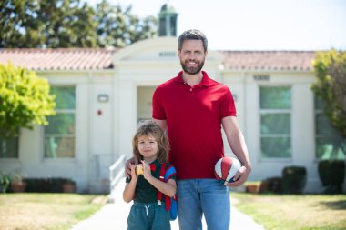 Baba oğluna okula kadar eşlik ediyor. İlkokul çocuğunun ebeveyni ve öğrencisi..