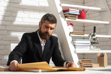 Sınıfta masa başında çalışan erkek öğretmenin portresi. Özel öğretmen, profesör, danışman. Okuma, öğrenme, eğitim konsepti.