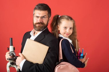 Kırmızı stüdyoda ciddi bir öğretmeni olan ilkokul öğrencisi, izole edilmiş. Komik liseli kız portresi ve okul malzemeleriyle özel öğretmen. Öğretmen ve öğrenci kız kırmızıda..