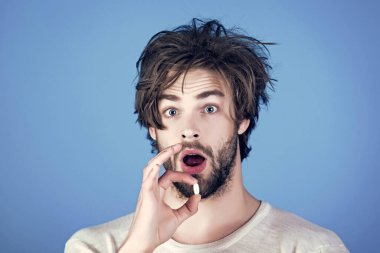 Şaşırmış yüzlü bir adam elinde hapla