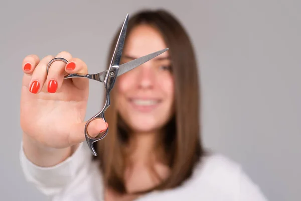 Close-up-Schere mit Haarschnitt. Schöne Mädchen mit glatten Haaren mit professioneller Schere. Haarpflegekonzept, selektiver Fokus. — Stockfoto