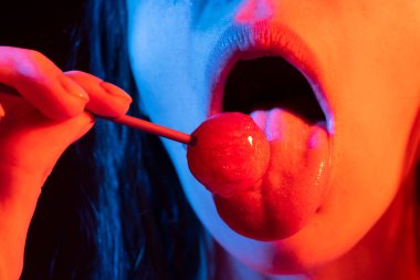 Close up lips with lollipop isolated, sexy blowjob, sensual mouth with lipstick eats sweets. Sexy design for women and girls. Beautiful lips.