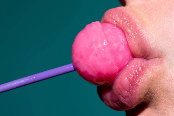 Lollipop in the mouth, close-up. Beautiful girl mouth with lolli pop. Oral sex blow job concept. Glossy red woman lips with tongue. Mouth lick suck chupa chups.