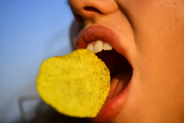 Miło jeść chipsy ziemniaczane. Zamknij usta samicy jedzą chipsy. Chipsy z zębami. Smaczne pyszne fast food. Jem chipsy. Fast food. — Zdjęcie stockowe