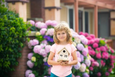 Çocuk arka bahçedeki bir oyuncak evde oynuyor. Mutlu çocuk hayali yeni ev.