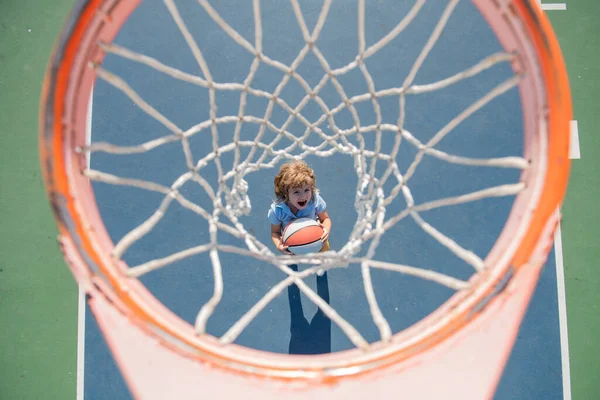 Erstauntes Kind hält Basketballball mit aufgeregtem, glücklichem Gesicht. — Stockfoto