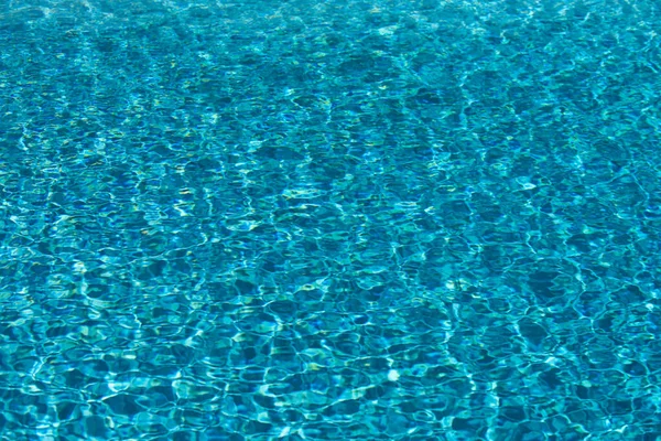 Водний фон. Блакитна вода, брижі та родзинки. Текстура водної поверхні і плиткового дна . — стокове фото