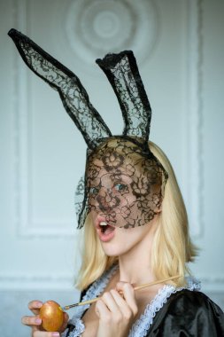 Tavşan kulağı takan ve renkli bir Paskalya yumurtası tutan çekici genç bir kadın. Güzel, şehvetli bir kadının moda portresi ve çok şehvetli görünüyor. Eğleniyorum. Kadın Paskalyası.