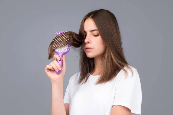 Aantrekkelijke vrouw die haar kamt. Mooi meisje met haarkam kamt haar. Begrip haarverzorging. — Stockfoto