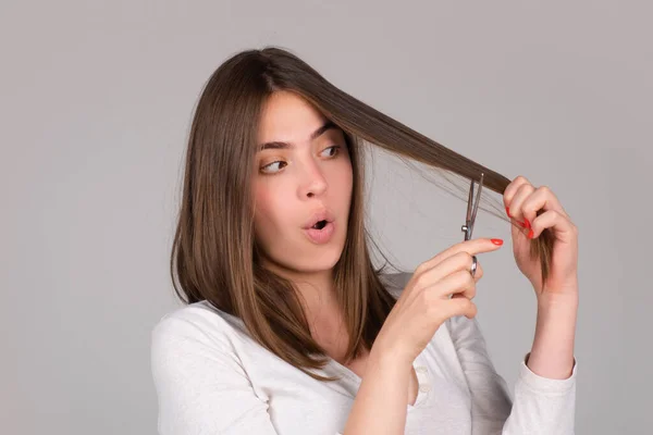 Mujer divertida con tijeras con corte de pelo. Hermosa chica con pelo liso con tijera profesional. Concepto de cuidado del cabello. —  Fotos de Stock