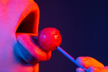 Parmak izi için şekerli seksi kırmızı dudaklar. Sanat tasarımında ağzında kırmızı, tatlı bir lolipop. Parlak kadın dudakları lolipop yalıyor. Şehvetli seksi ağız ve şeker kavramı. Güzel kadın dudakları..