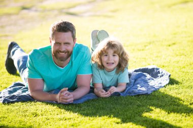 Baba ve oğul parkta doğada dinleniyor. Çocukluk ve ebeveynlik kavramı. Mutlu baba ve çocuk dışarıda oynuyorlar..