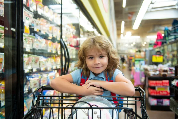 Pequena criança cliente no supermercado ou supermercado com mercadorias no carrinho de compras. — Fotografia de Stock