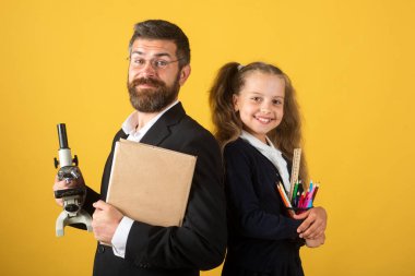 Stüdyoda öğretmeni olan ilkokul öğrencisi, izole edilmiş. Mutlu liseli kızla öğretmen. Komik okul kızı portresi ve okul malzemeleriyle özel öğretmen..