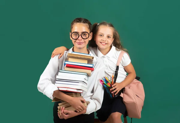 Menina da escola com pilha de livros. Estudante adolescente carrega um livro. Difícil de estudar. Irmãs abraçadas e prontas para a escola. — Fotografia de Stock