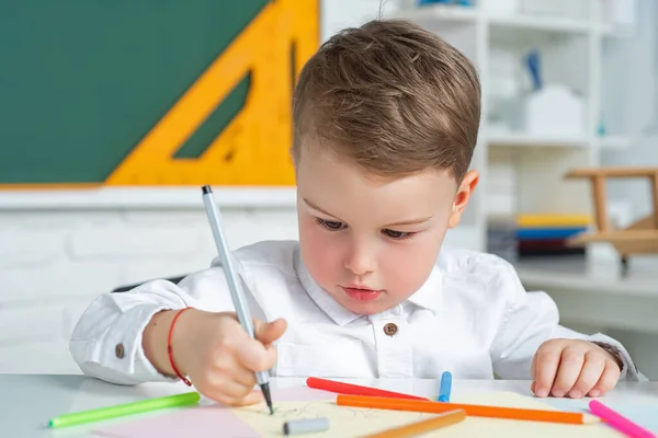 Söt liten förskolepojke i ett klassrum. Grundskola och utbildning. Processen för skolbarn. — Stockfoto