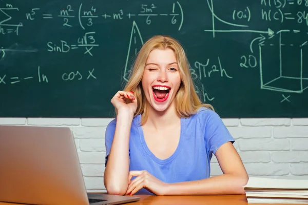 Studenten meisje met blije gezichtsuitdrukking bij het bureau met schoolspullen. Tieners met schoolschrift. Jonge vrouwelijke student klaar om examen testen schrijven. — Stockfoto