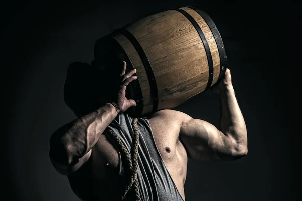 Strong man holds barrel isolated on black. — Stock Photo, Image