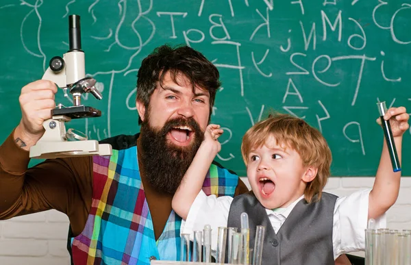 Öğretmenler okulda çocuklara ödevlerinde yardım ediyor. Çocuk ve öğretmen sınıf odasında. Küçük mutlu bilim adamı deney tüpüyle deney yapıyor.. — Stok fotoğraf