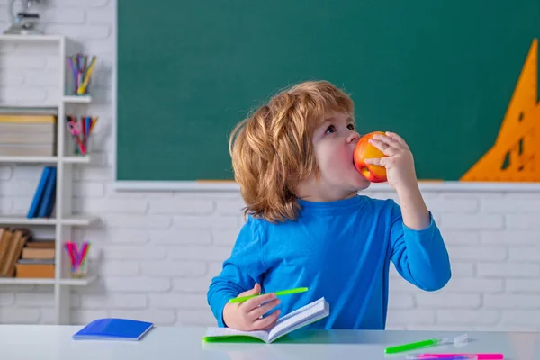 Des écoliers avec des pommes contre du tableau vert. L'école primaire. Un peu prêt à étudier. Éducation. — Photo