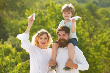 Ebeveynlik ve çocukluk kavramı. Baba, anne ve oğlu dışarıda oynuyorlar. Baba ve oğul eğleniyor ve doğada oynuyorlar. Baba oğlunu omuzlarında taşıyor..