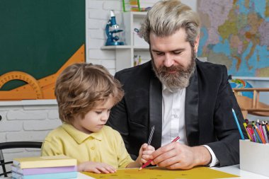Father teaching son. Funny little child with father having fun on blackboard background. Supporting pupils at school. Private kids tutoring.