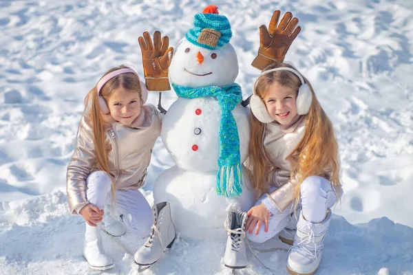 Göra snögubbe och vinter roligt för barn. Glada barn leker med en snögubbe på en snöig vinterpromenad. — Stockfoto
