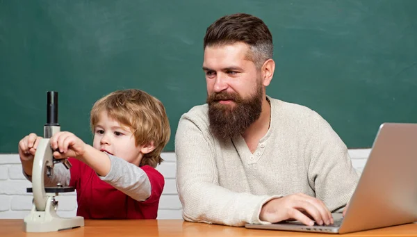 男老师和学龄前的孩子一起玩。在家学习。老师和学生在课堂上使用笔记本电脑。年轻或成年。老师在学校的课堂上帮助孩子们做作业. — 图库照片