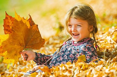Warm sunny weather. Smiling kid over autumn natural background. Playing in the autumn park. Children play outdoors.