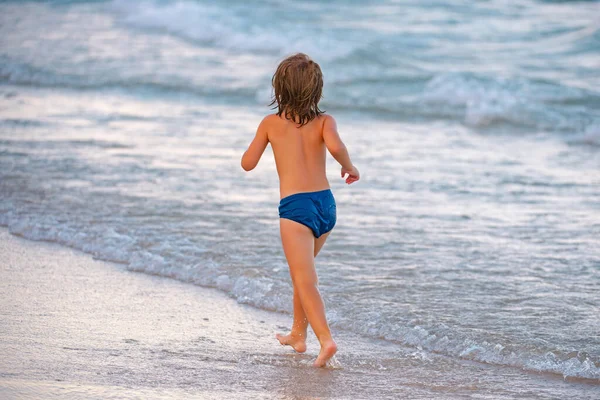 Lindo niño que se divierte y corre en la playa de arena en verano. — Foto de Stock