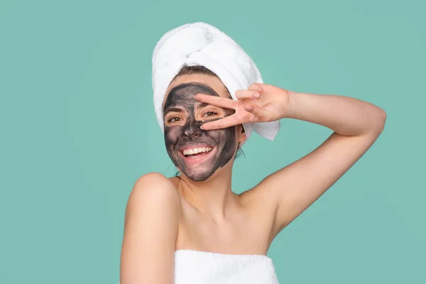 Mud facial mask, face clay mask spa. Funny amazed woman with cosmetic mud facial procedure, spa health concept. Skin care beauty treatment. Towel on head. Medical mineral mud. — Foto de Stock