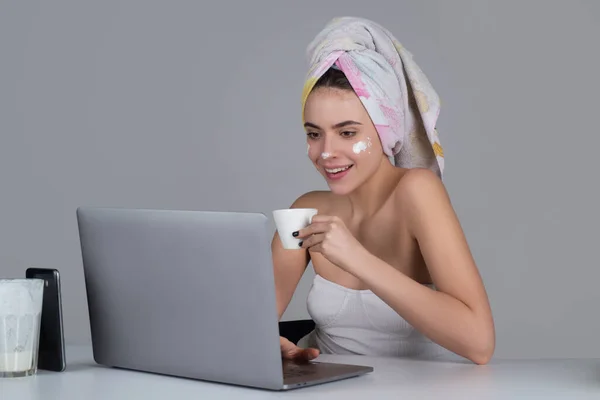 Morning woman with coffee and facial mask on daily routine. Enjoying time at home. Beautiful young smiling woman working on laptop and drinking coffee. — Foto Stock