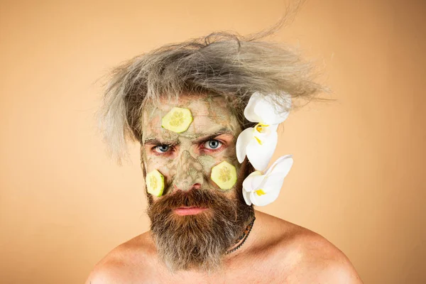 Funny man with clay mask and cucumber slices on face. Male spa, dermatology, wellness and facial treatment concept. — Stock Photo, Image