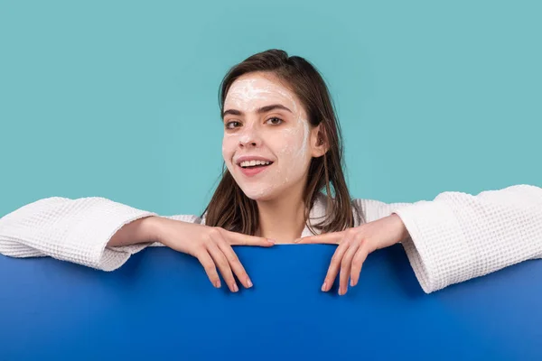 Woman facial mask, face clay. Beautiful woman with cosmetic facial procedure, spa skin concept. Spa girl with copy space for text. Proposing a product. Gestures for advertisement. Blue background. — Fotografia de Stock