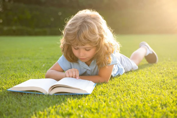 Zeki zeki çocuklar. Dışarıda kitap okuyan sevimli bir çocuk. Çocuk parkta kitap okudu. Açık hava çocuk eğitimi. — Stok fotoğraf