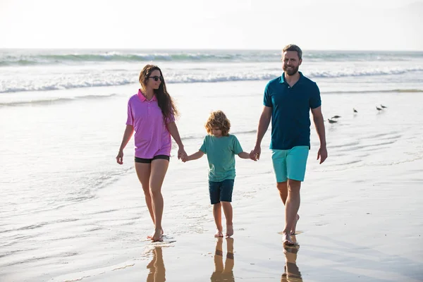 Young family father, mother with baby son hold hands and walk on sand beach. Active parents and people outdoor activity. — Stock Photo, Image