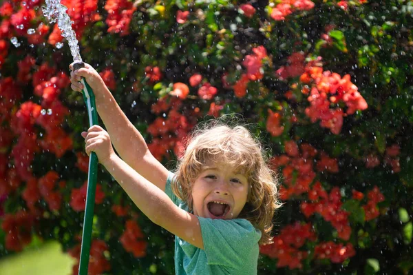 여름에 정원에서 물을 주는 귀여운 소년. 뒷마당 정원에 공구와 물 호스를 갖고 있는아이. 마당에서 재밌게 놀고 있는 애. 아이들의 친절 과어린 시절에 대한 개념. — 스톡 사진