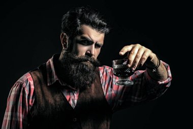 Erkek ya da iş adamı siyah arka planda viski içer. Sakallı ve bir bardak viski. Alkolik içecek..