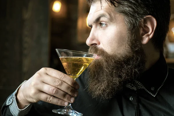 Pohledný zamyšlený muž drží sklenici martini. Fešák pije alkohol, když sedí u baru. — Stock fotografie