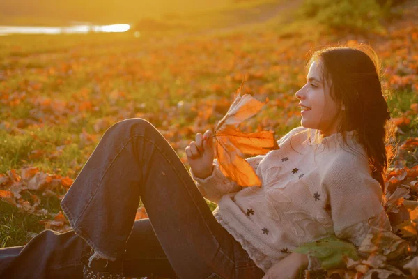 Mulher menina bonita desfrutar de outono. Menina relaxada leigos caídos folhas no dia de outono ensolarado. Calor e aconchego. Outono feminino folhas fundo. — Fotografia de Stock