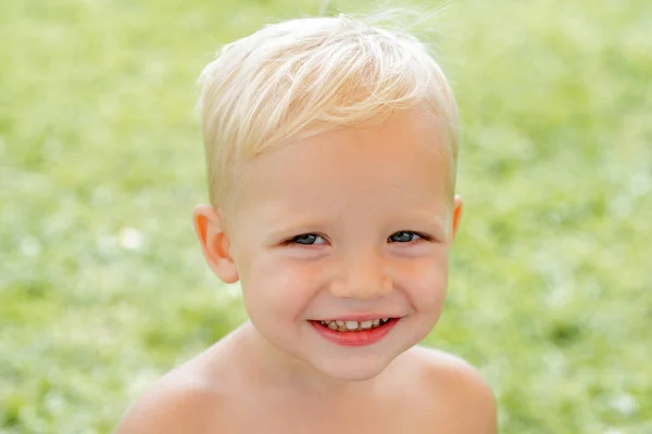 Feliz retrato infantil. Chico gracioso. Niño feliz parado en la hierba en el soleado día de verano. Feliz día.. —  Fotos de Stock