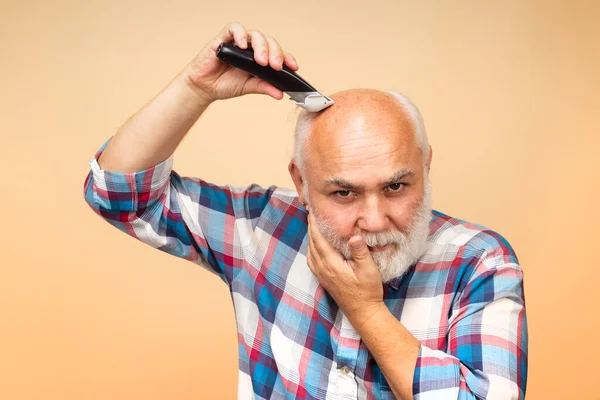 Homem velho com cortador de cabelo, corte de cabelo com navalha elétrica. — Fotografia de Stock