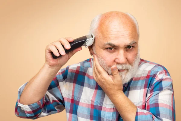 Ritratto di vecchio tagliato con tosatrice in barbiere, taglio di capelli con rasoio elettrico. Trattamento capelli uomo. — Foto Stock