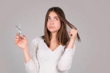 Makas kesen bir kadın. Profesyonel makas izole stüdyosu olan düz saçlı güzel bir kız. Saç bakım konsepti.